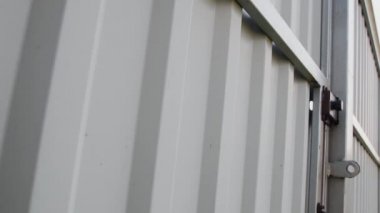 Hand attaches red level gauge with magnet to gray metal fence