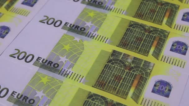 Kleurrijke paperclips vallen op tafel 200 euro bankbiljetten — Stockvideo