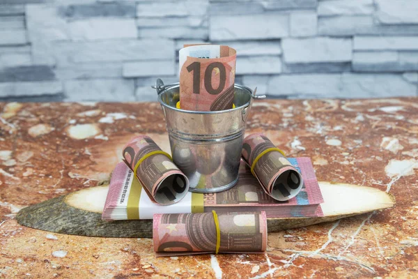 Rolos de moeda de 10 euros e pacotes de notas dobrados num balde de metal pequeno — Fotografia de Stock