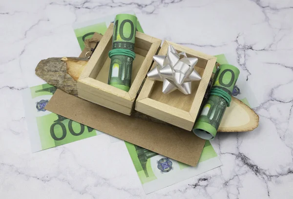 100 notas de euro com pacotes e rolos de dinheiro em caixas de madeira sobre madeira cortada — Fotografia de Stock