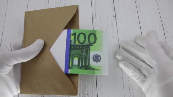 Ręka w białej rękawicy liczy 100 banknotów euro w brązowej kopercie — Wideo stockowe