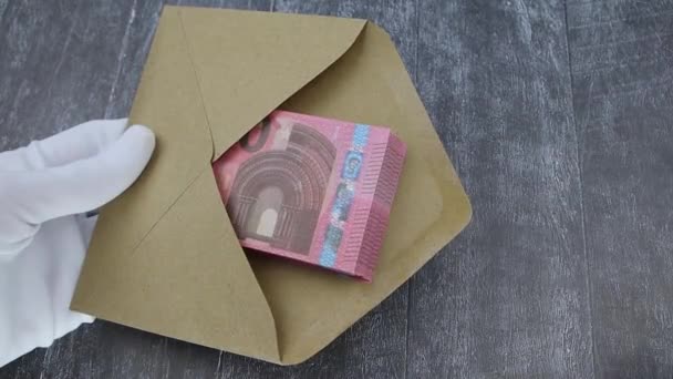 一只手戴着一只白手套，在一个棕色的信封里数着一捆10欧元的钞票 — 图库视频影像