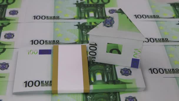 Una mano en un guante blanco toma una casa de 100 euros de pie sobre un paquete de billetes — Vídeos de Stock