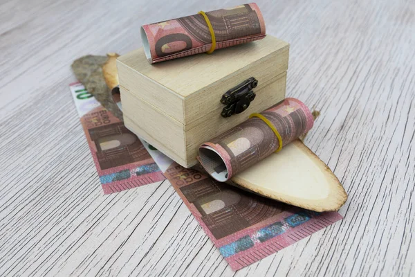 Gewalste 10 Eurobiljetten liggen op een klein houten doosje en op een houten snede — Stockfoto