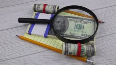 Kırtasiyeli 100 dolarlık banknotların üzerinde bir büyüteç var.