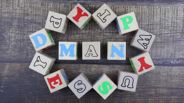 Word - Man in colorful alphabet letters on wooden cubes. Stop motion, top view — Stock Video