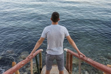 Adam denize giden merdivenler üzerinde ayakta
