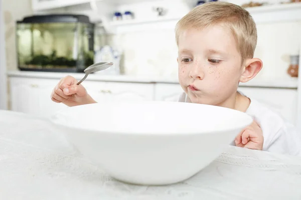 Chico está mirando un plato vacío — Foto de Stock