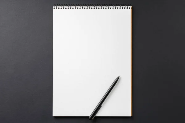 Notebook s černým perem na černém pozadí — Stock fotografie