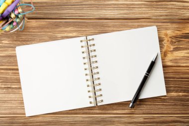 Ahşap masadaki boş çarşaflı kalem defteri.