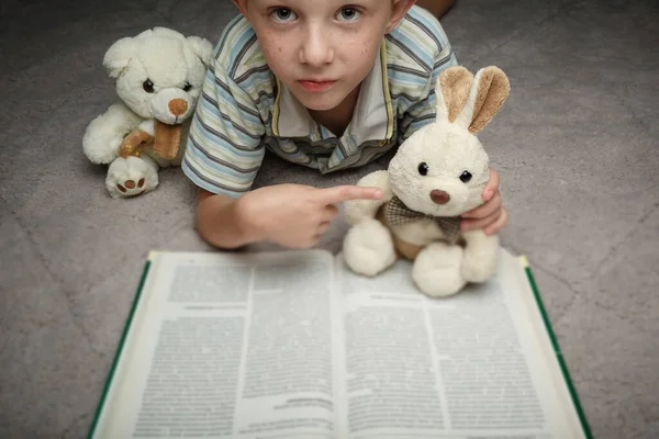 Kleine jongen lezen boek met zijn favoriete speelgoed — Stockfoto