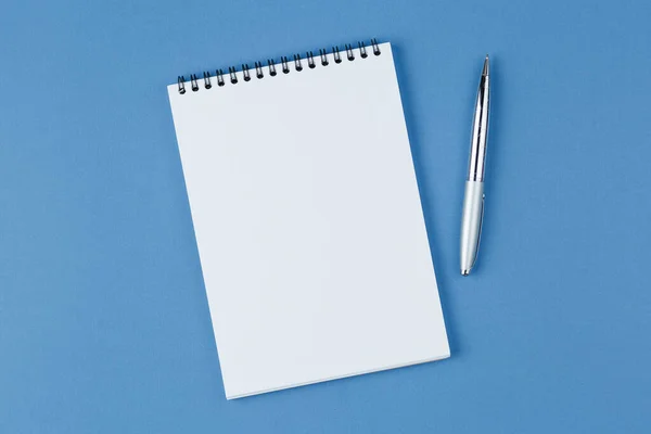 Блокнот з ручкою на синьому фоні — стокове фото