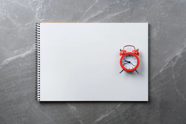 spiral notebook with red alarm on marble table