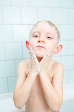 Küçük çocuk duşta yıkanıyor.