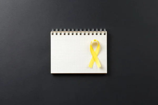 Ruban jaune cancer sur carnet — Photo