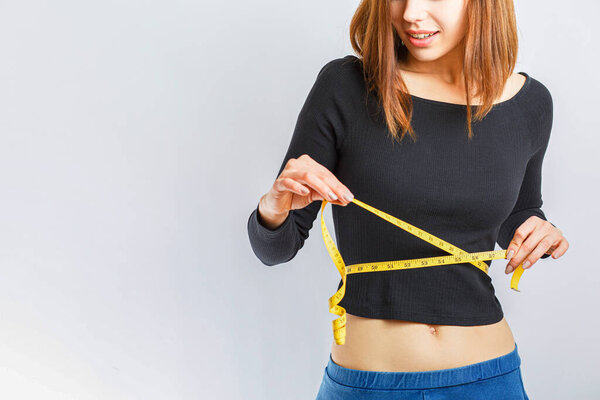 красивая стройная девушка измеряет талию