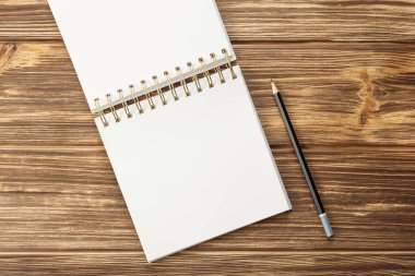 Ahşap masadaki boş çarşaflı kalem defteri.