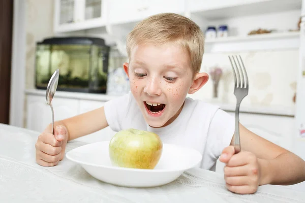 Niño en el desayuno, mira la manzana verde — Foto de Stock