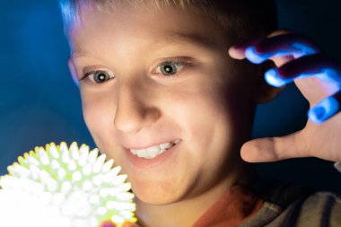 Çocuk elinde parlayan bir oyuncak tutuyor..