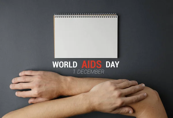 Notebook, crossed hands World AIDS Day Concept.