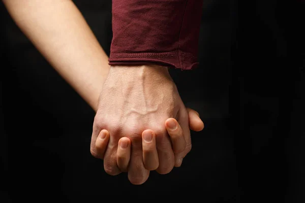 Mano masculina sostiene mano femenina sobre fondo oscuro — Foto de Stock