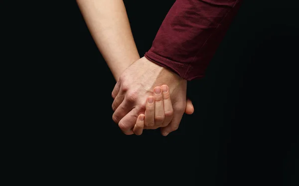 Mão masculina segura a mão feminina no fundo escuro — Fotografia de Stock