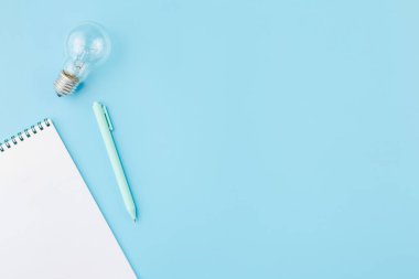 Not defterli lamba ve mavi arka planda bir kalem..