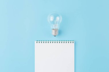 Mavi arkaplanda not defteri olan lamba.