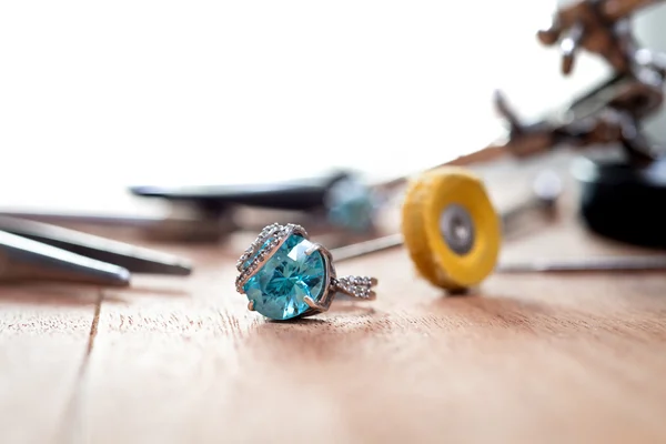 桌面的珠宝商。用蓝色石头与珠宝首饰工具桌上的银戒指 — 图库照片