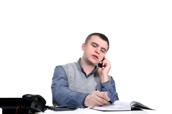 Office worker.He is sitting at a table and talking on the phone — Stock Photo, Image