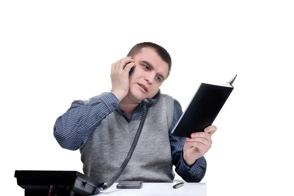 Worker.He escritório está sentado a uma mesa e falando ao telefone — Fotografia de Stock