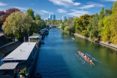 Levallois Perret, Paris ve Seine arasında sıkışmış küçük ve hoş bir kasabadır. Resimde Seine nehri ve Ile de la Jatte kayıkhaneleri ve kayıkhaneleri ve La Defense silueti yer alıyor..