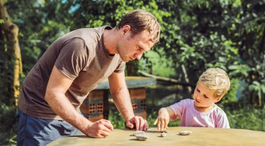Baba oğul güneş günü dışında oynuyor. Trafik kurallarını açıkla. Taş taklidi arabalar kullan. Avuç içi hareketi talimatı. Etkileyici ciddi yüz ifadesi. Evde çocuk eğitimi