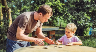 Baba oğul güneş günü dışında oynuyor. Trafik kurallarını açıkla. Taş taklidi arabalar kullan. Avuç içi hareketi talimatı. Etkileyici ciddi yüz ifadesi. Evde çocuk eğitimi