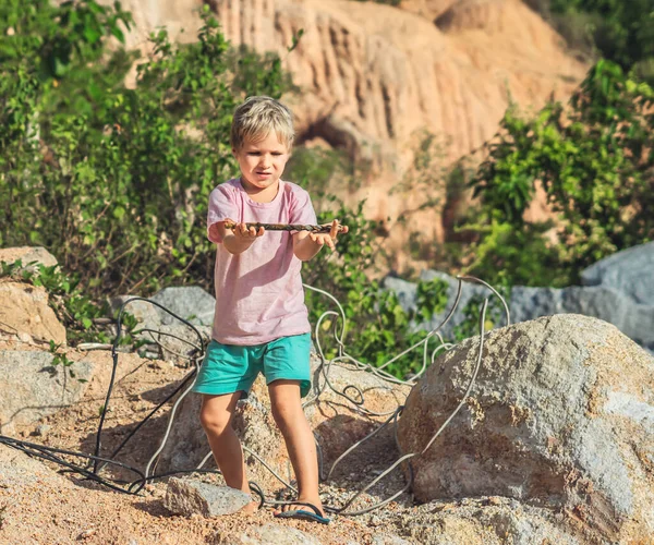 Vakava poika löytää pelata metallia aaltopahvin teräs vahvistaminen, pidä avoimessa kämmenkädessä, johdot köydet. Lasten turvallisuus lähellä rakennustyömailla jätteet, ongelma kaatopaikka roskat lähellä lapsi leikkikentät — kuvapankkivalokuva