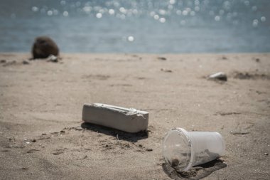 Çöp kutusunu kapat şeffaf cam bardağı paket servisi için, doğaya bir sürü çöp döküldü kumsal kum günü denizi, sorunlu dünya okyanus kirliliği, çevre koruma