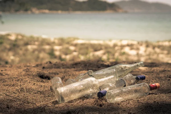 Close landfill old dirty transparent discarded empty glass alcohol drinks bottles trash on ground forest nature sea park. Alcoholism addiction problem bad habits, ecology issues environment pollution — Stok Foto