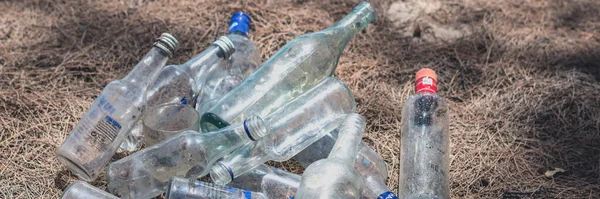BANNER landfill old dirty transparent discarded empty glass alcohol drink bottles trash on ground forest nature sea park. Alcoholism addiction problem bad habits, ecology issues environment pollution — Stockfoto