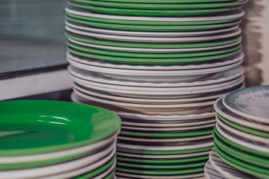 Yıkandıktan sonra yakın çekim üst üste yığılmış melamin plastik, yuvarlak, yeşil, temiz, düz tabaklar. Bu mutfak tabakları kötü mü, yemek için zararlı mı yoksa güvenli mi? Ucuz fiyat ya da sağlık anlaşması