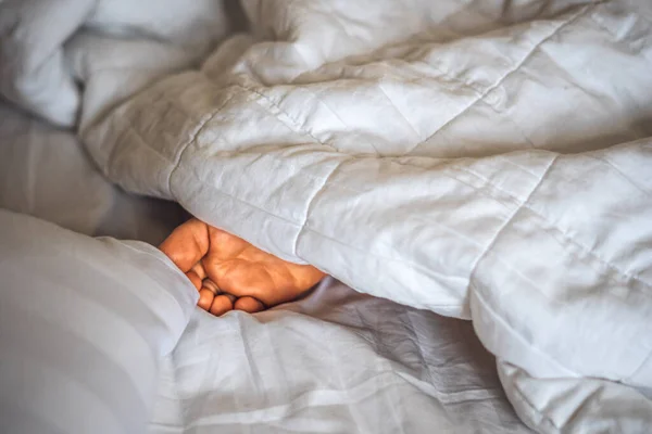 क्लोज-अप साइड व्यू चाइल्ड बॉय बिस्तर पर सफेद कंबल के नीचे एक पैर छड़ी। नींद और आराम अवधारणा, सुबह बच्चे का सपना या दुःस्वप्न की कोमलता, छिपाना खेलना, वास्तविक त्वचा स्टॉक फ़ोटो