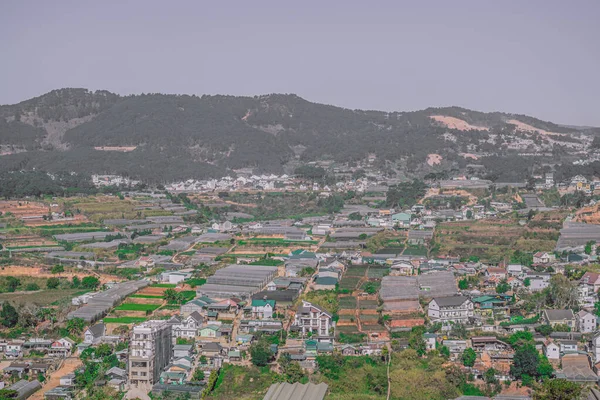 Πανόραμα τοπίο, Dalat πόλη, Langbian Οροπέδιο, Βιετνάμ Κεντρική Highland περιοχή. Φυτικά χωράφια, πολλά σπίτια, αρχιτεκτονική, χωράφια, θερμοκήπια. Φόντο βουνού. Πράσινη γκρι καπνιστή τονισμένη φωτογραφία — Φωτογραφία Αρχείου