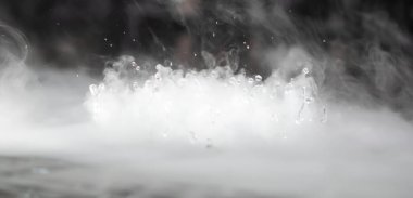 Soyut BANNER. Gerçek Mistik duman bulutu, su damlası patlaması, buhar sineği hareketi, karanlık arka plan. Kimyasal deney, aromaterapi, yanık içecek buharı paranormal sis. Zıtlık tonu. Daha fazla renk kaynağı