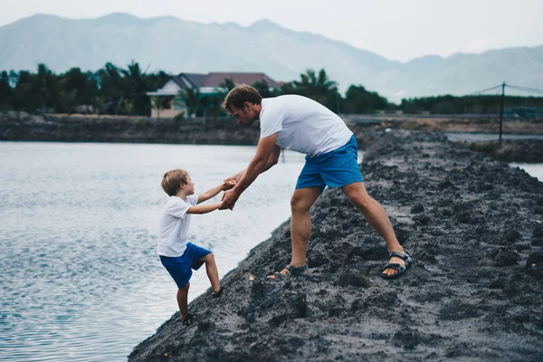 Ayah membantu anak pergi ke danau air, menjelaskan aturan keselamatan. Malam, latar belakang gunung. Selamat hari jadi ayah. Keluarga bersama-sama berjalan bermain. Pendidikan alam rumah, hari ayah, tanggung jawab — Stok Foto