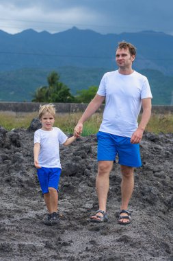 Mutlu bir gülümseme baba oğul ya da küçük kardeş macera aramak için birlikte yürürler. Yağmurdan önce bulutlu bir gökyüzü, dağ arkası. Çocuğu elle tutan adam, kameraya bak. Doğal ev eğitimi