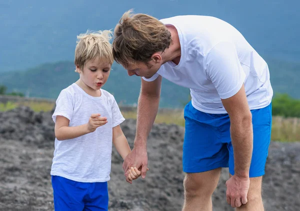 Father son or adult younger brother walk together. Boy found show holds unusual stone in hand fingers, Man attentive look. Natural family science education, fathers day, dad responsibility influence — Stock Photo, Image