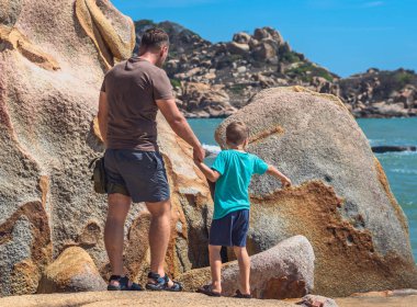 Babanın umrunda değil. Deniz kenarında oğlumuz var. Birlikte vakit geçirip yeni şeyler keşfediyoruz. Babalar günü aile birliği babalığı kavramının mutlu çocuk nüfuzunu büyütmesi dünya görüşü. Çocuk elini tutan adam parmaklarıyla gösteri yapar.