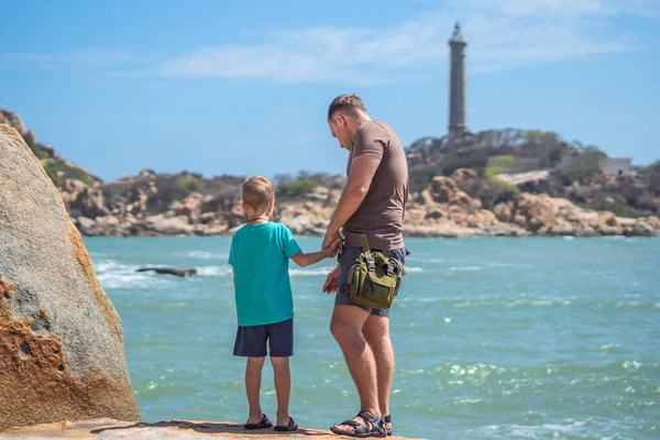 Babanın umrunda. Deniz kenarında oğlu var. Birlikte zaman geçirip yeni şeyler keşfediyoruz. Çocuk elini tutan adam. Deniz feneri arka planı bireysel bilincin sembolü, çocuk yetiştirme, baba aile birliği mutlu çocuk üzerindeki etkisi