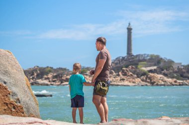 Babanın umrunda. Deniz kenarında oğlu var. Birlikte zaman geçirip yeni şeyler keşfediyoruz. Çocuk elini tutan adam. Deniz feneri arka planı bireysel bilincin sembolü, çocuk yetiştirme, baba aile birliği mutlu çocuk üzerindeki etkisi
