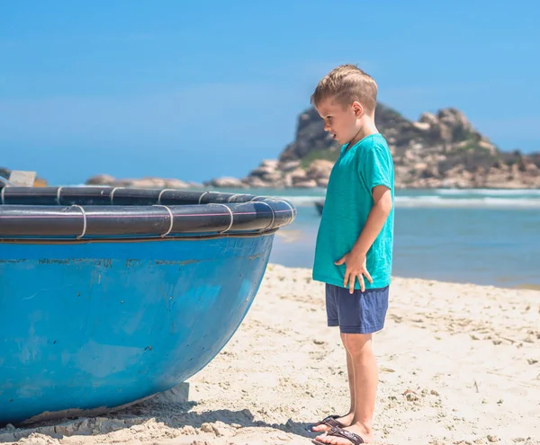 Portret op volledige hoogte zijaanzicht kid stand. Serieuze aandachtige blik op vietnam ronde boot. Concept idee, natuurlijke kinderen onderwijs, opvoeding jongen, oogpunt, keuze, wachten, leren nieuw, toerisme, vrije tijd — Stockfoto