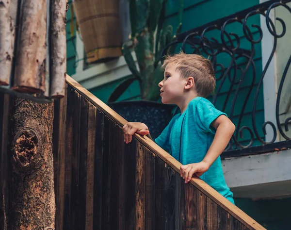 Copier Espace style de vie petit garçon monter les escaliers en bois à l'extérieur tenir les mains courantes, rechercher l'expression faciale, jouer cacher chercher, Concept soigneusement rechercher de nouvelles attentes, éducation enfants biens — Photo